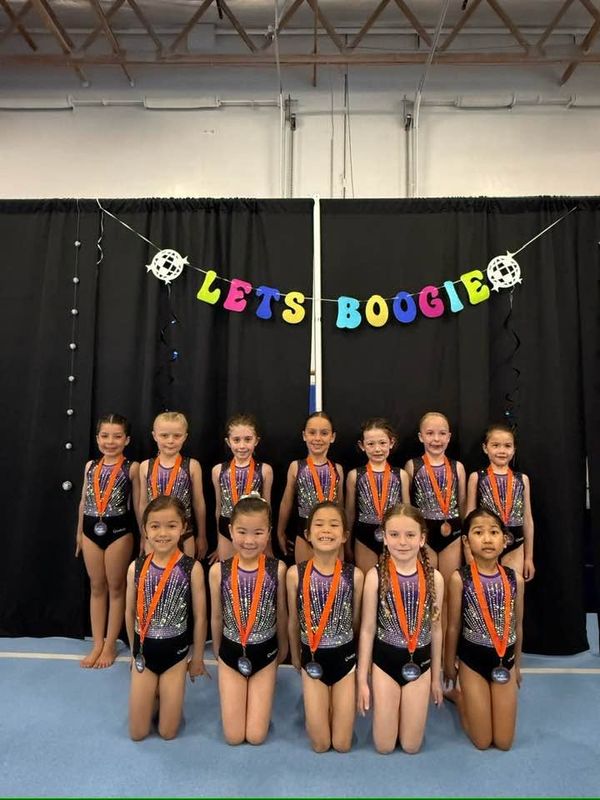 Gymnastics East athletes posing with medals at a meet