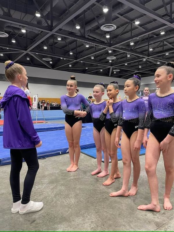 Gymnastics East coach talking with team athletes at a meet